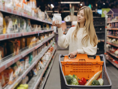 Customer choosing food product in supermarket reading label information